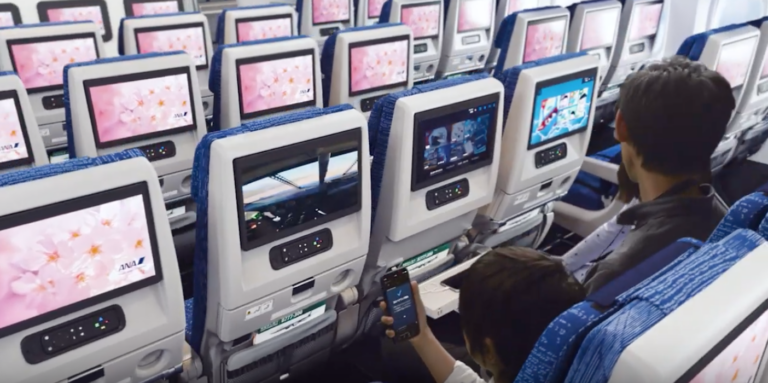 a passenger watching a seatback entertainment screen in an ana boeing 777 cabin