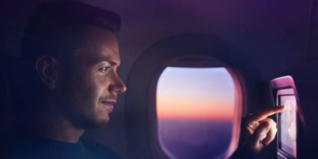 a passenger using the seatback screen on an airplane