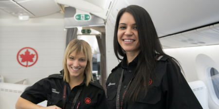 two female air canada crew smiling in an aircraft cabin