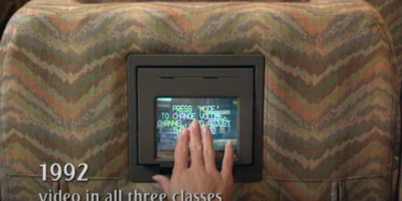 a passenger on emirates airline in 1992 using the small square seatback entertainment screen