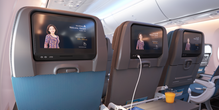 a row of economy class seats with entertainment screens
