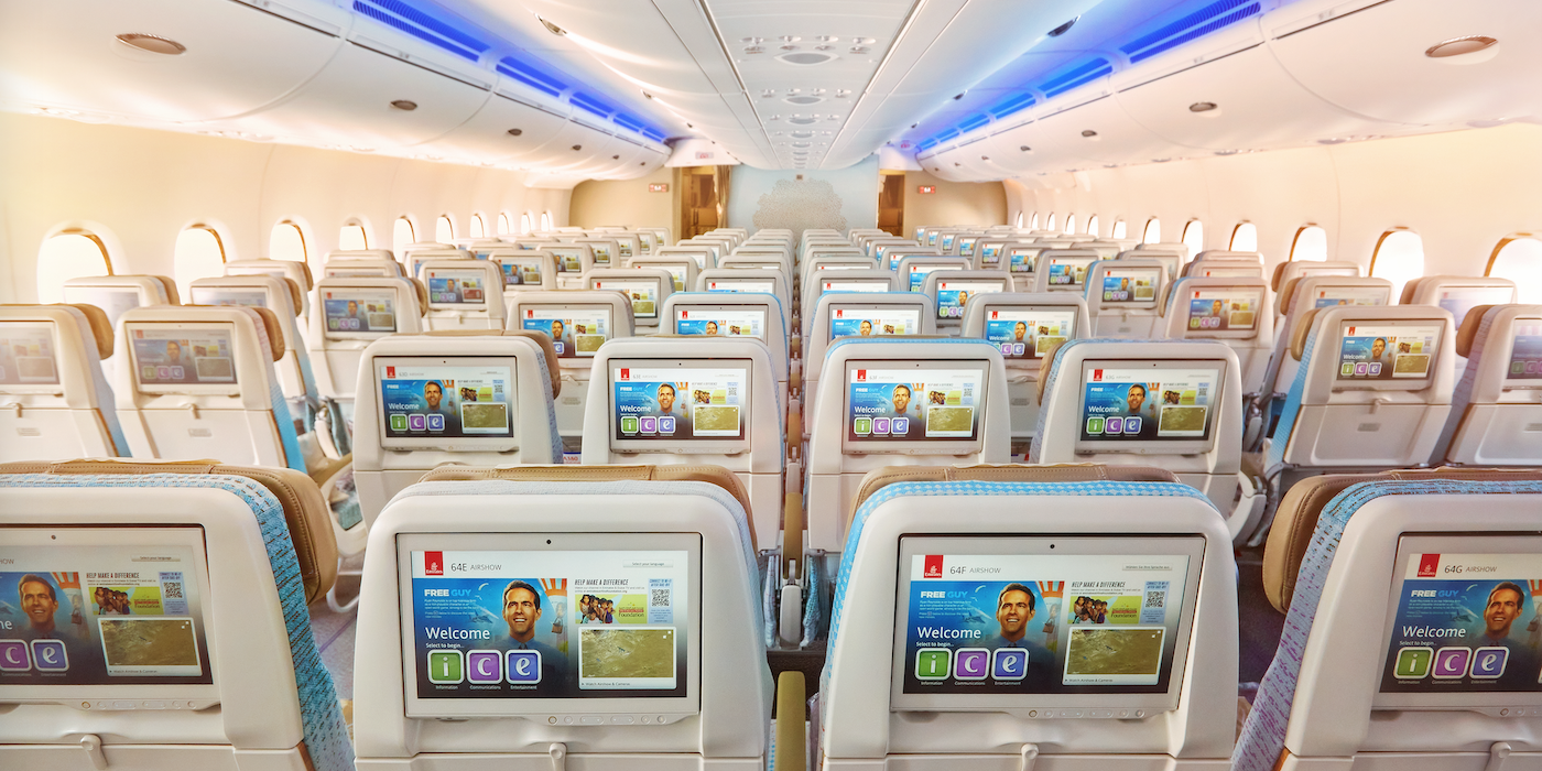 view of an economy class cabin, with all seatback screens switched on