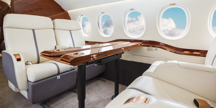 the cabin interiors of a business jet, with leather seating and a wood dining table