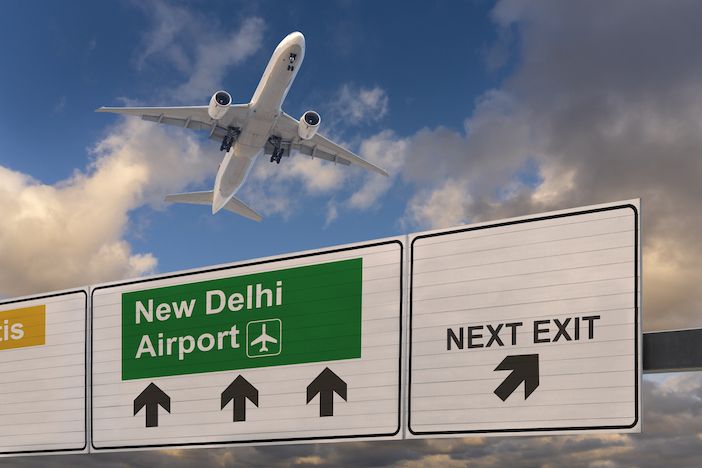 Road sign indicating the direction of New Delhi airport and a plane that just took off