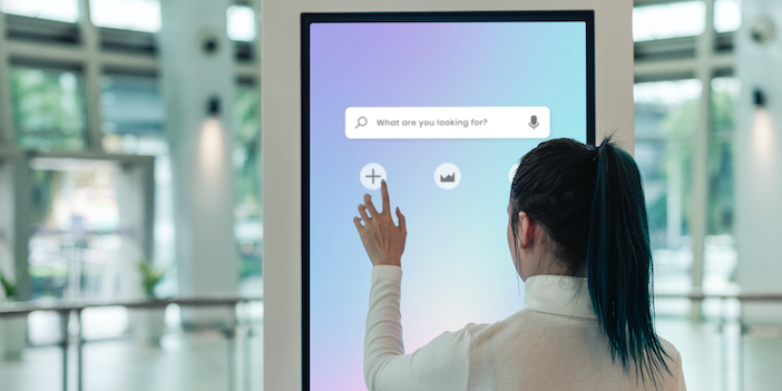 a woman using a touchscreen help board in an airport terminal