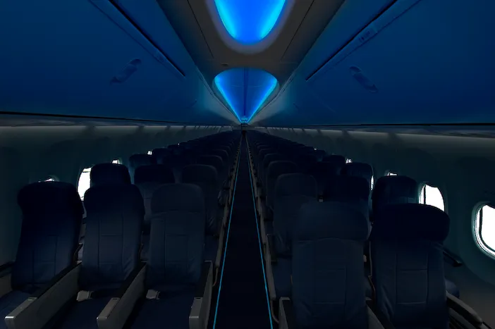 The saf-Tglo Eco E1 sustainable emergency floor-path marking system in an aircraft cabin, emitting a blue glow along the aisle