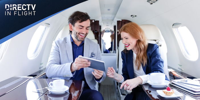 A male and female onboard a private jet, watching tv on an ipad