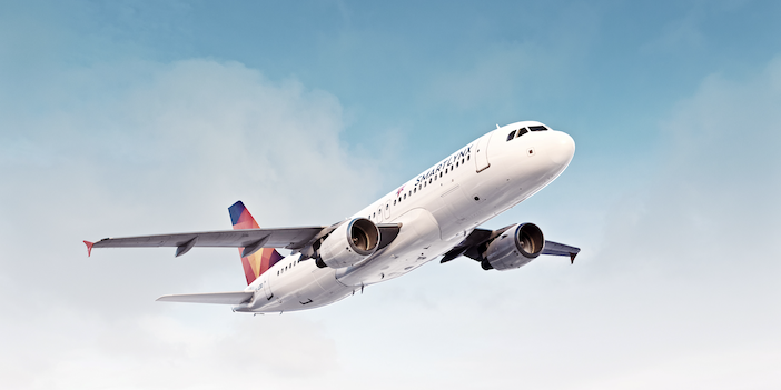 A SmartLynx Airlines A320 in a white livery with a red and blue tailfin flying through the clouds