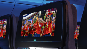 Soccer players celebrating a victory, show on a seatback entertainment screen in an economy class aircraft cabin