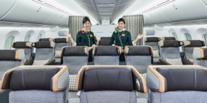 Two cabin crew members showing the new EVA Air Dreamliner premium economy cabin, trimmed in shades of greay and blue