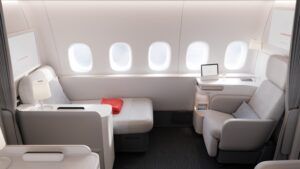 The 2025 Air France La Première B777-300ER suite, with a greay seat to the right, an ottoman to the left, and five aircraft windows in between