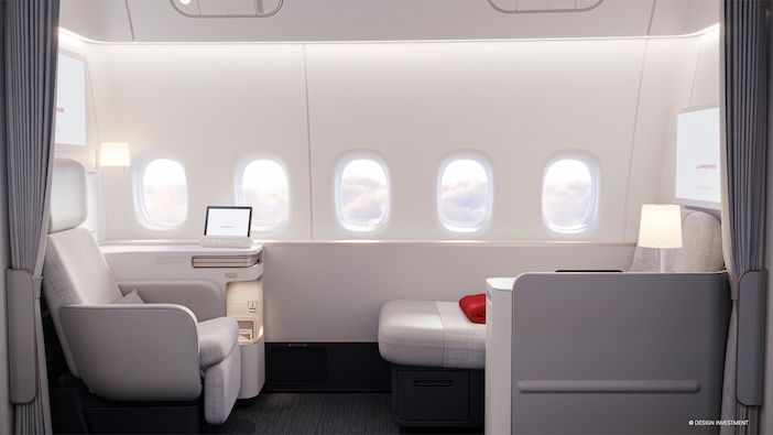 Air France's La Premiere first-class suite, in pale grey colours with a seat to the left, chaise longue to the right, and five windows behind