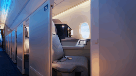PAL's A350-1000 business class seat with privacy partition, showing aisle access, personal window, and modern gray upholstery in cabin with blue ambient lighting"