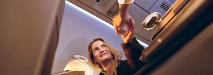 A female passenger in Lufthansa business class accepting a drink from cabin crew