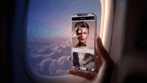 A phone with the AirMall portal shown on the screen being held up against an aircraft window