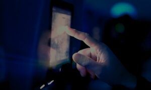 A finger pressing an option on a touchscreen in a darkened room