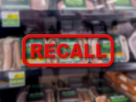 Blurred background of vegetarian meat products for sale with the red text Recall in the foreground