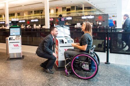 An Air Canada staff member helping a lady in a wheelchair at the airport
